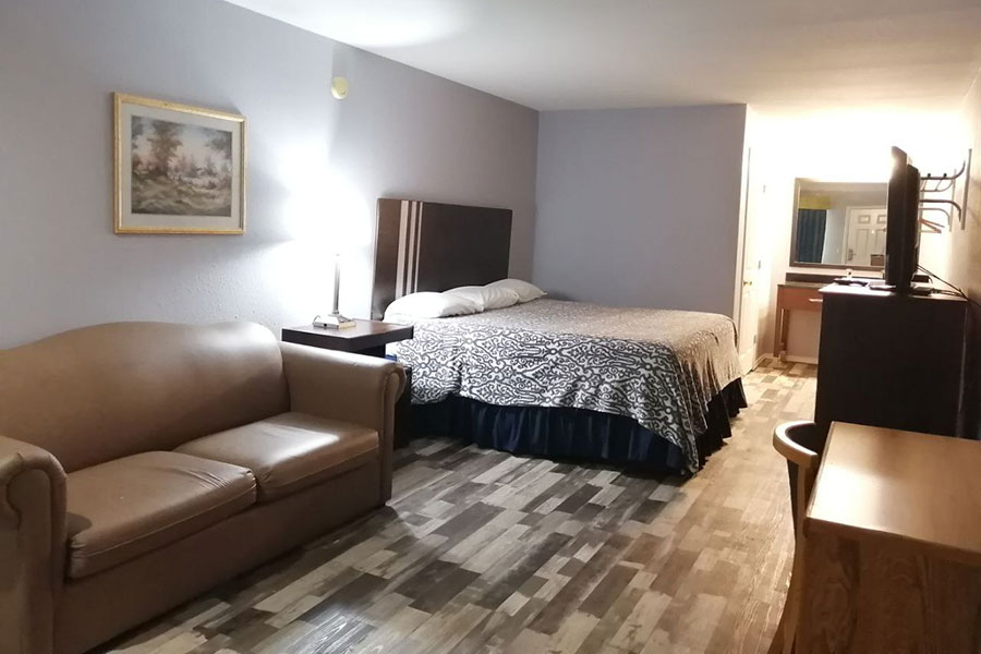 Deluxe King Hotel Rooms in Crystal City TX featuring comfortable bedding, flat-screen TV, refrigerator, and modern in-room amenities at Riata Inn
